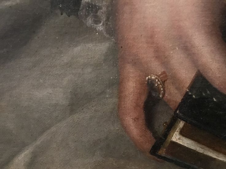 Detail van 19e eeuws schilderij. De geportretteerde houdt een boek vast, waarschijnlijk een bijbel of een kerkboek